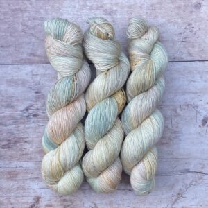 Three skeins of Merino & Silk in palest pink, blue and cream. Lightly speckled in gold