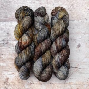 Three skeins of classic sock in dark blues, plum and gold