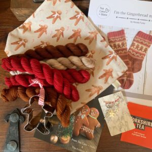 a gingerbread man themed workbag with coordinating stitch markers a biscuit cutter, pattern and yarn