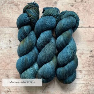 Three skeins classic sock in mid to dark blue with orange variegation on pale wood surface