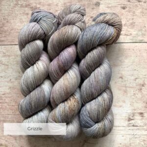 Three skeins classic sock in soft warm grey, speckled with brown on pale wood surface