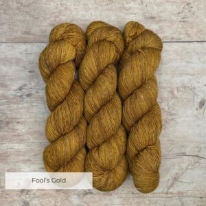 Three skeins of a wool and linen blended yarn in a golden mustard