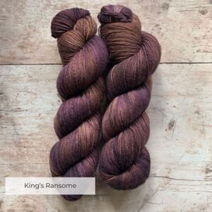 Two skeins classic sock in plum and tan on pale wood surface