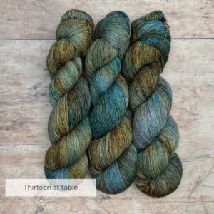 Three skeins of merino and linen in a mid blue green with splashes of golden brown
