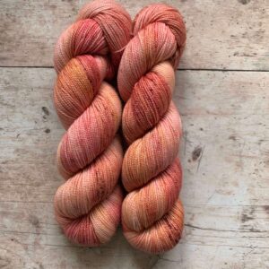 Two skeins classic sock in pinks and coral on pale wood surface