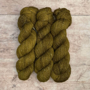Three skeins of merino and linen in a mid blue green with splashes of golden brown