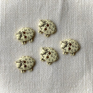 Five cream sheep shaped buttons