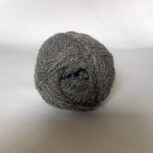 Ball of tweedy grey-green Shetland Wool on cream background