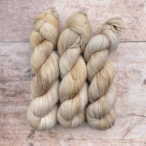Three skeins Plump Sock Yarn in shades of cream and buff