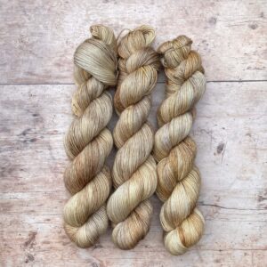 Three skeins of merino floof in buttercream, coffee and gold