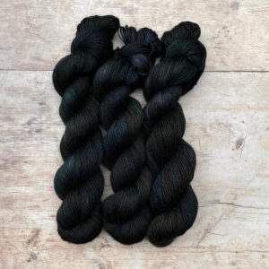 Three skeins of Merino Floof in deep greens, inky blues and rust