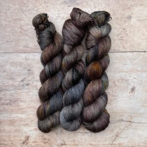 Three skeins of Merino Floof in browns, dark blues, plum and gold