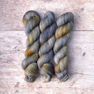 Three skeins of Mohair sock in Feather a grey, cream, yellow and orange speckled yarn