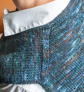 Close up of the shoulder of a knitted top being worn over a white shirt