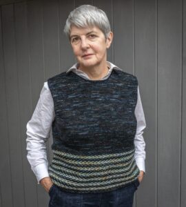 woman wearing blue variegated pullover standing in front of grey background