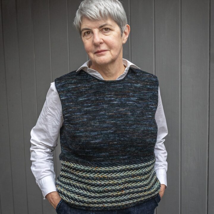 woman wearing blue variegated pullover standing in front of grey background