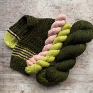 A full skein of dark green teal yarn with two small minis one lime yellow, one pink