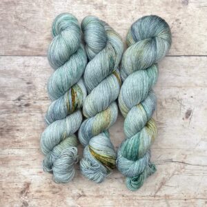 Three skeins of Merino & Silk in pale blue green with splashes of yellow