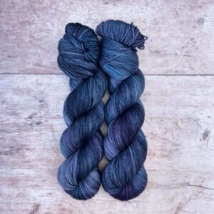 Two skeins of Classic Sock in shades of denim, purple and sea green