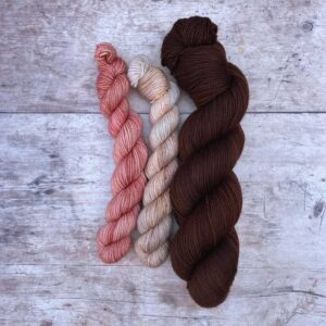 A sock set in Classic Sock with a full skein in a rich brown and two smaller skeins one pink and the other creamy pink with speckles