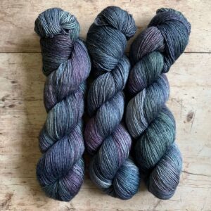 Three skeins Merino Silk in shades of denim blue, purple and sea green