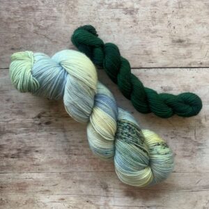 A full skein of Classic Sock in pale blue, green with splashes of moss green and blue with a coordinating nori coloured mini