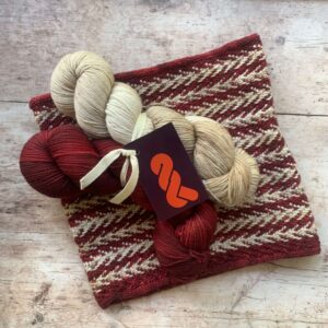 Slipped Stitch knitted cowl with red and cream skeins of yarn