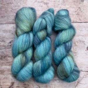 Three skeins of mohair silk lace in bright, sky blue with chocolate and gold shading